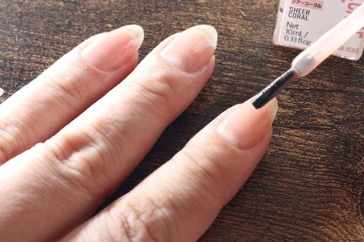 女性が素爪ケアコートを指の爪に塗布している