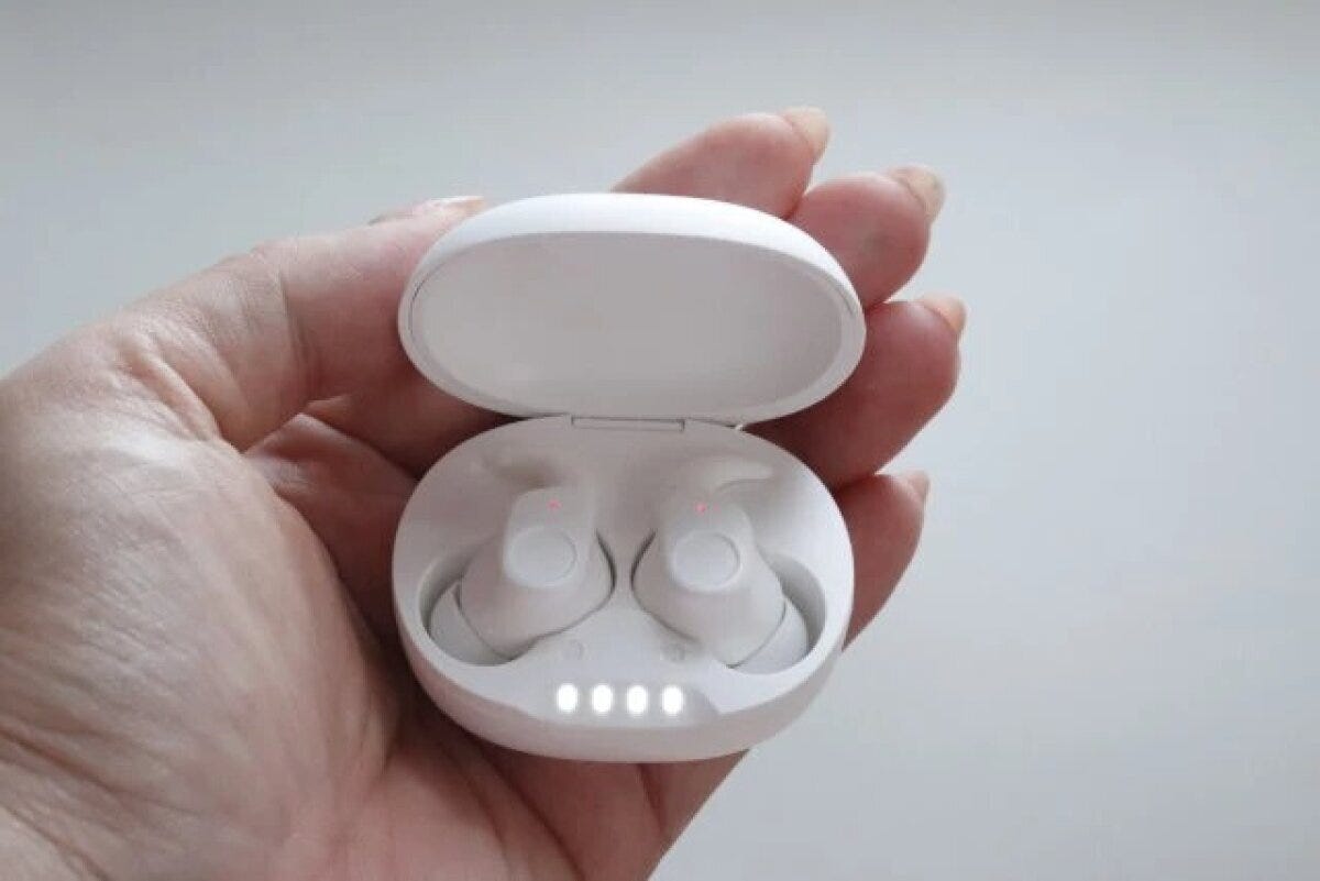 白いワイヤレスイヤホンが充電ケースに入り、女性の手のひらに乗っている
