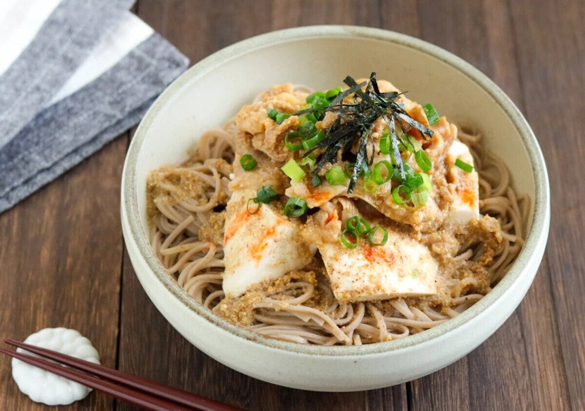 そばの上に豆腐と甘辛い豚肉、ネギと海苔が盛られた冷製肉そば そばの上に豆腐と甘辛い豚肉、ネギと海苔が盛られた冷製肉そば