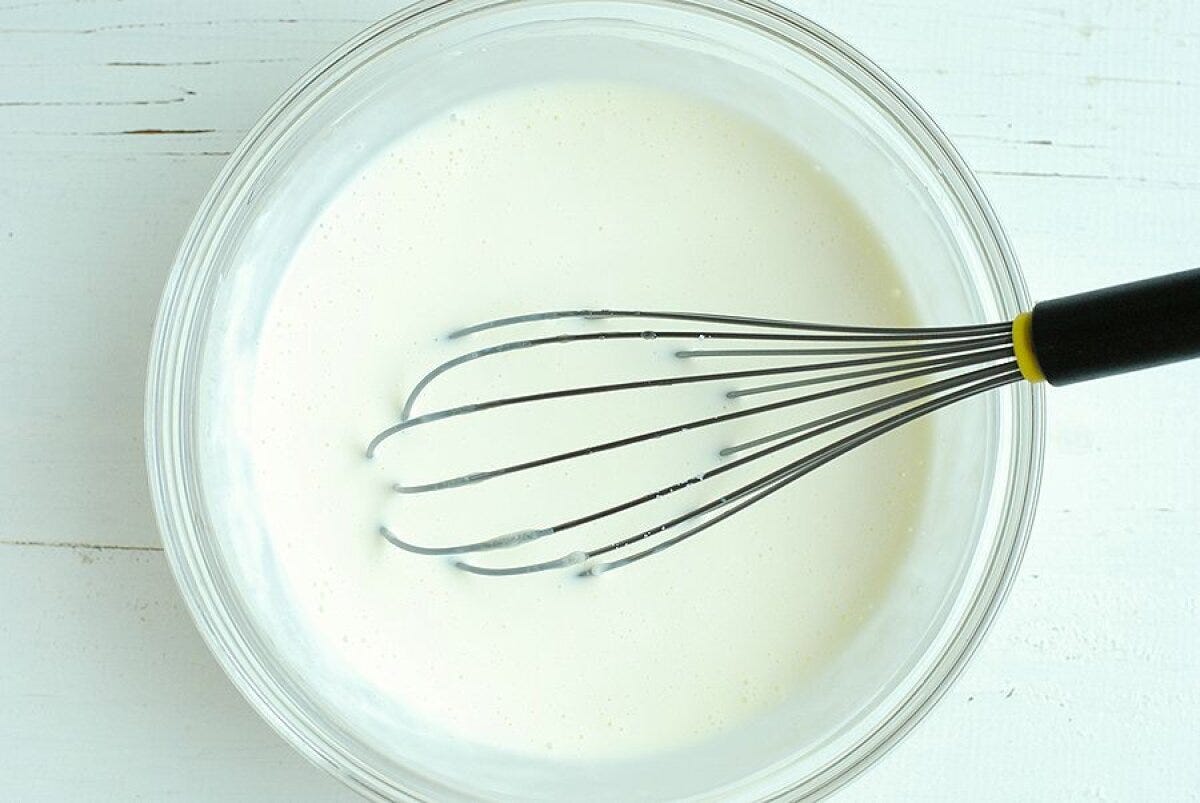 透明なボウルに入った牛乳やヨーグルトが混ざった生地を泡立て器で混ぜている様子 透明なボウルに入った牛乳やヨーグルトが混ざった生地を泡立て器で混ぜている様子
