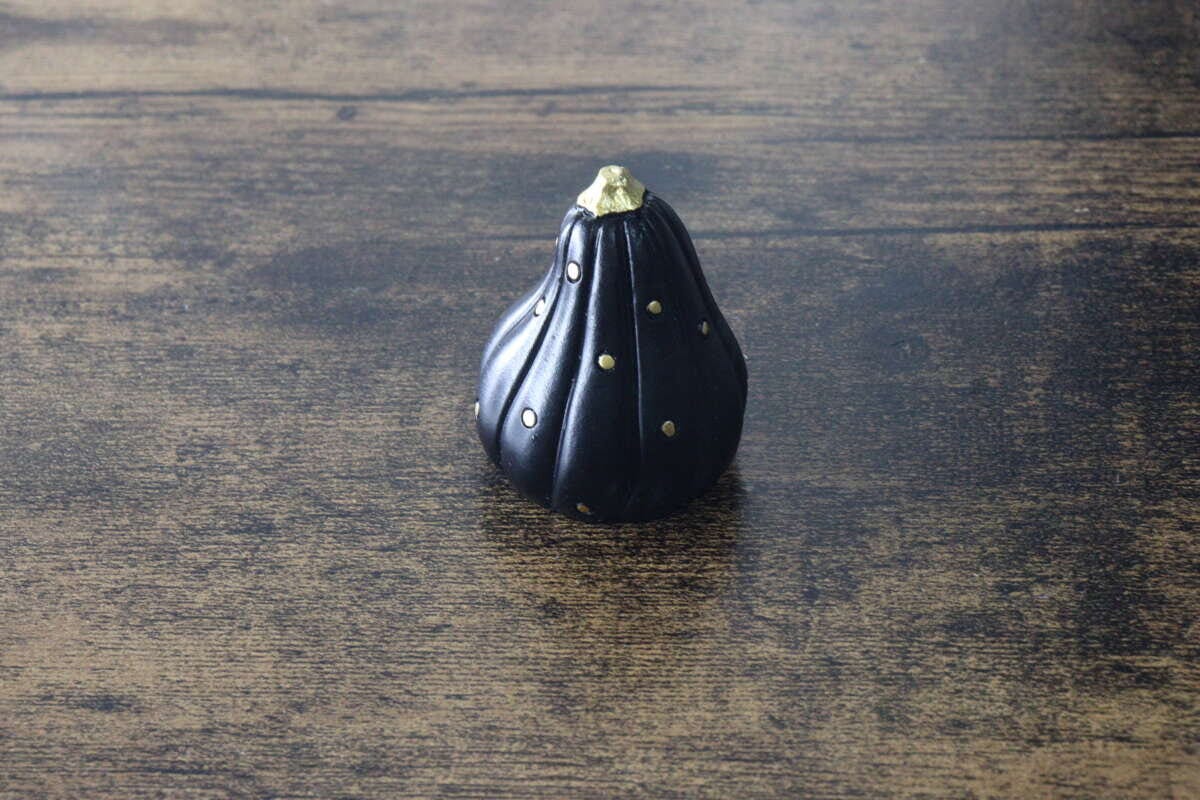 黒いかぼちゃ型オブジェが木目テーブルに置かれている