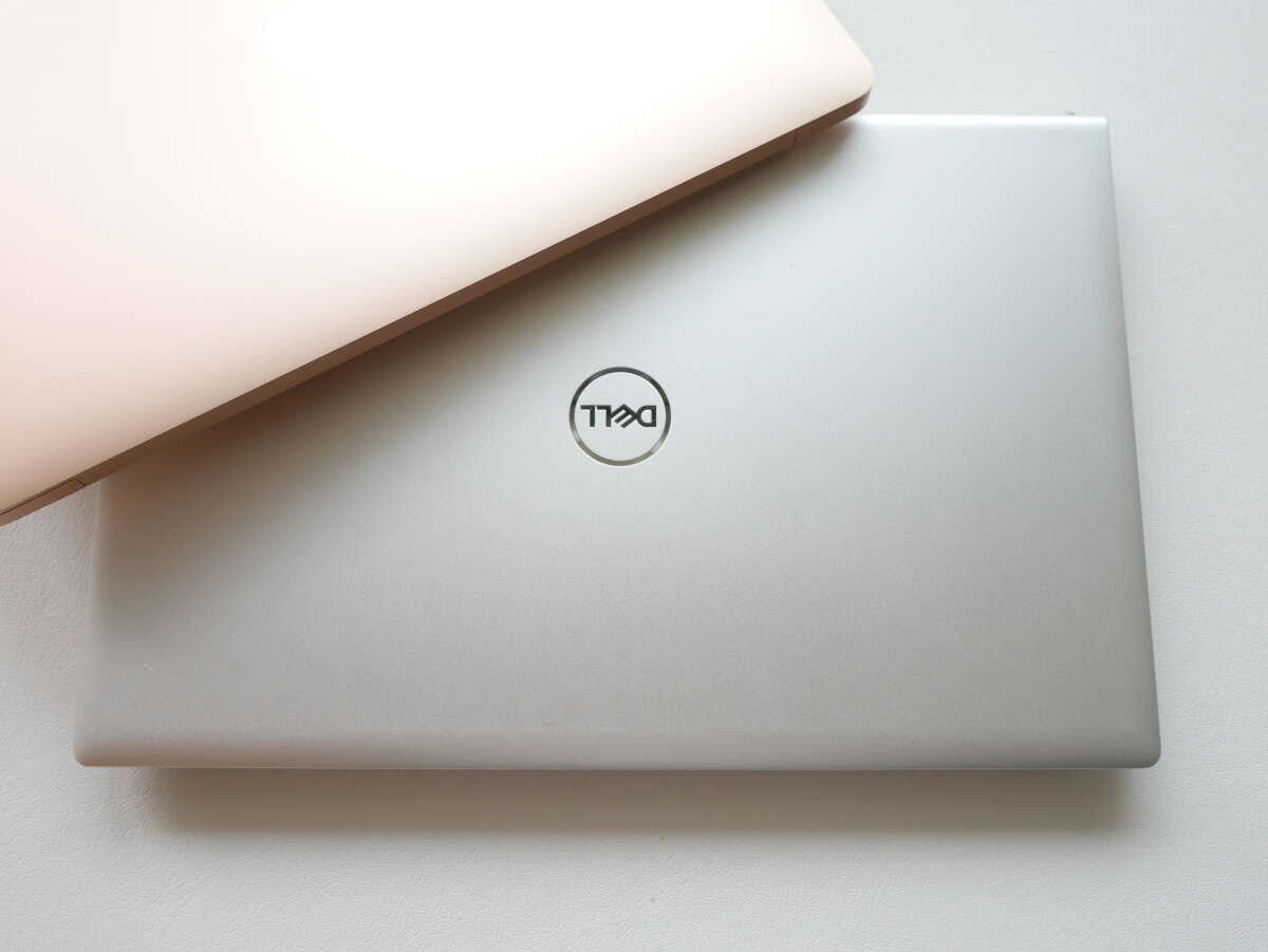銀色のDELL製ノートパソコンとピンク色のノートパソコンが重なっている 銀色のDELL製ノートパソコンとピンク色のノートパソコンが重なっている