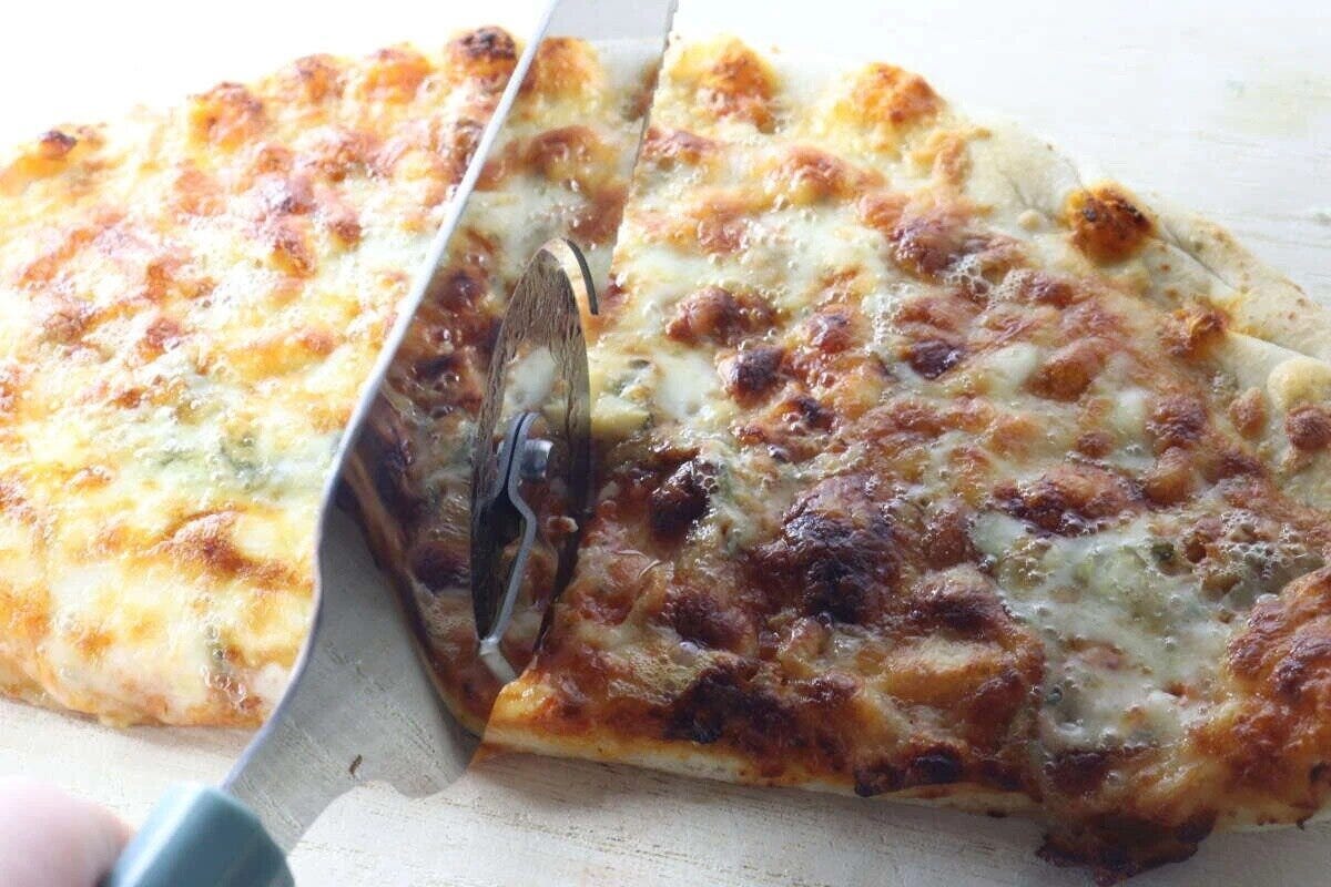 ピザサーバーのローラー部分で焼きたてのピザをカットしている様子。