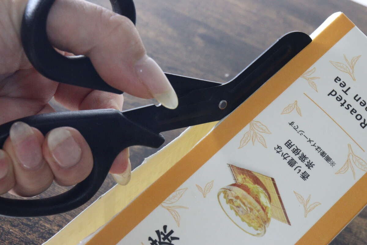 ギザ刃を備えたキッチンハサミで紙パックの側面をスムーズに切っている状態 ギザ刃を備えたキッチンハサミで紙パックの側面をスムーズに切っている状態