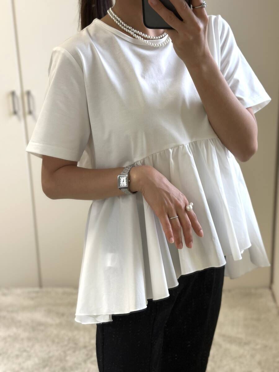 白いペプラムTシャツを着て鏡越しに自撮りする女性