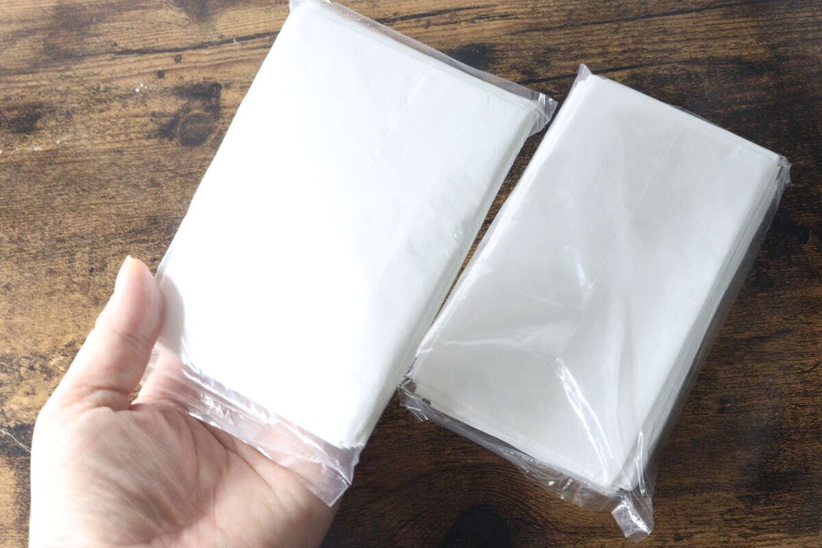 手のひらにコンパクトに畳まれたレジ袋の束が2つ乗っている