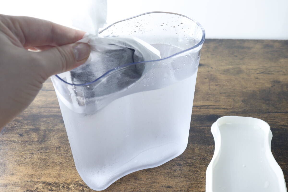 水が入ったピッチャーにコーヒー粉入りのフィルターを入れている 水が入ったピッチャーにコーヒー粉入りのフィルターを入れている