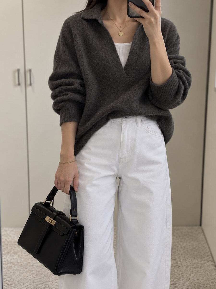 濃いグレーのニットと白パンツで自撮りする女性 濃いグレーのニットと白パンツで自撮りする女性