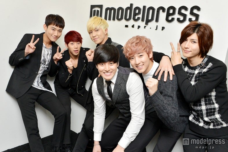 モデルプレスロゴの前でポーズ