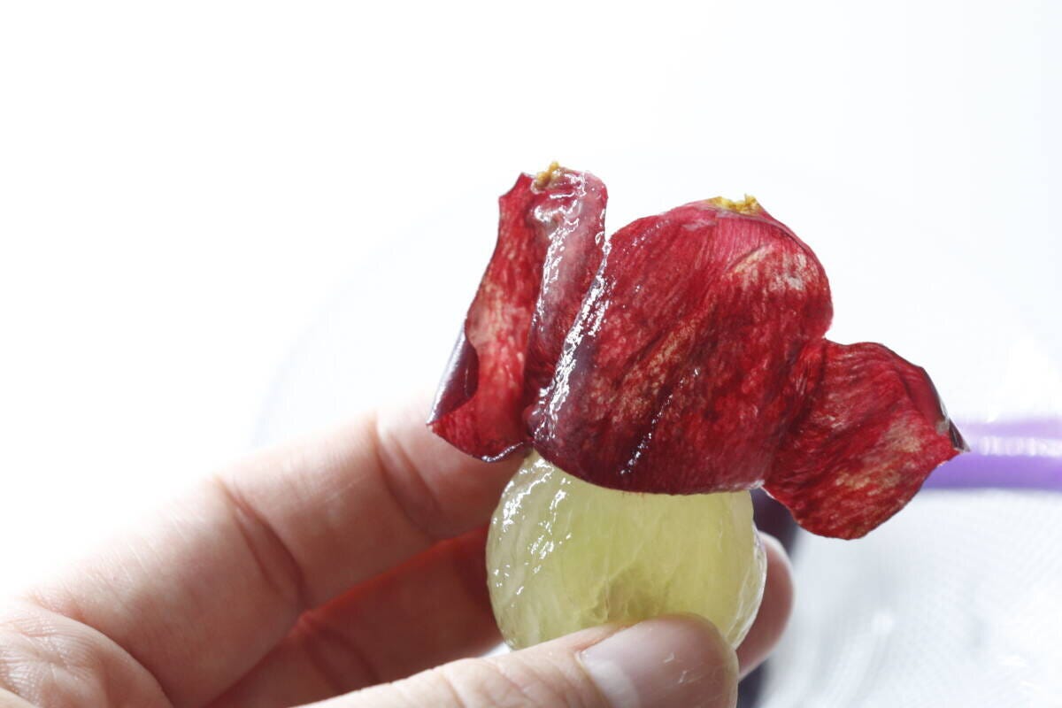 剥がれた皮を指でつまんで果肉から取り出している手元