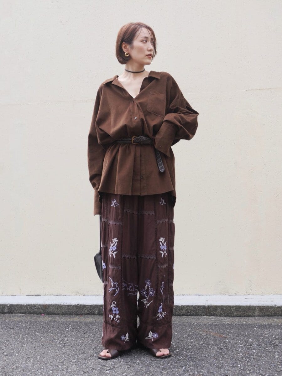 ブラウンシャツと刺繍パンツをベルトで着こなす女性