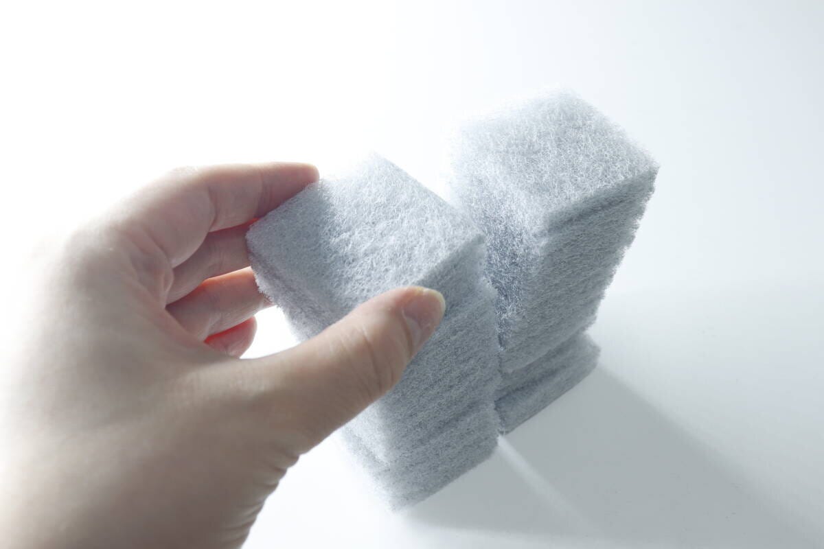 手で積み重ねられた竹炭入りスポンジの束を掴んでいる 手で積み重ねられた竹炭入りスポンジの束を掴んでいる