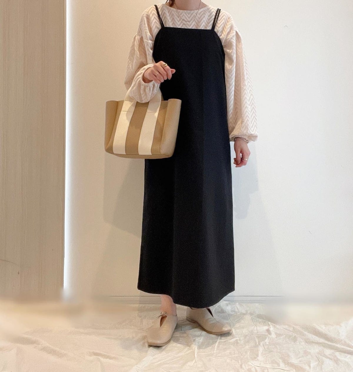 ブラックキャミワンピとホワイトトップスを着ている女性