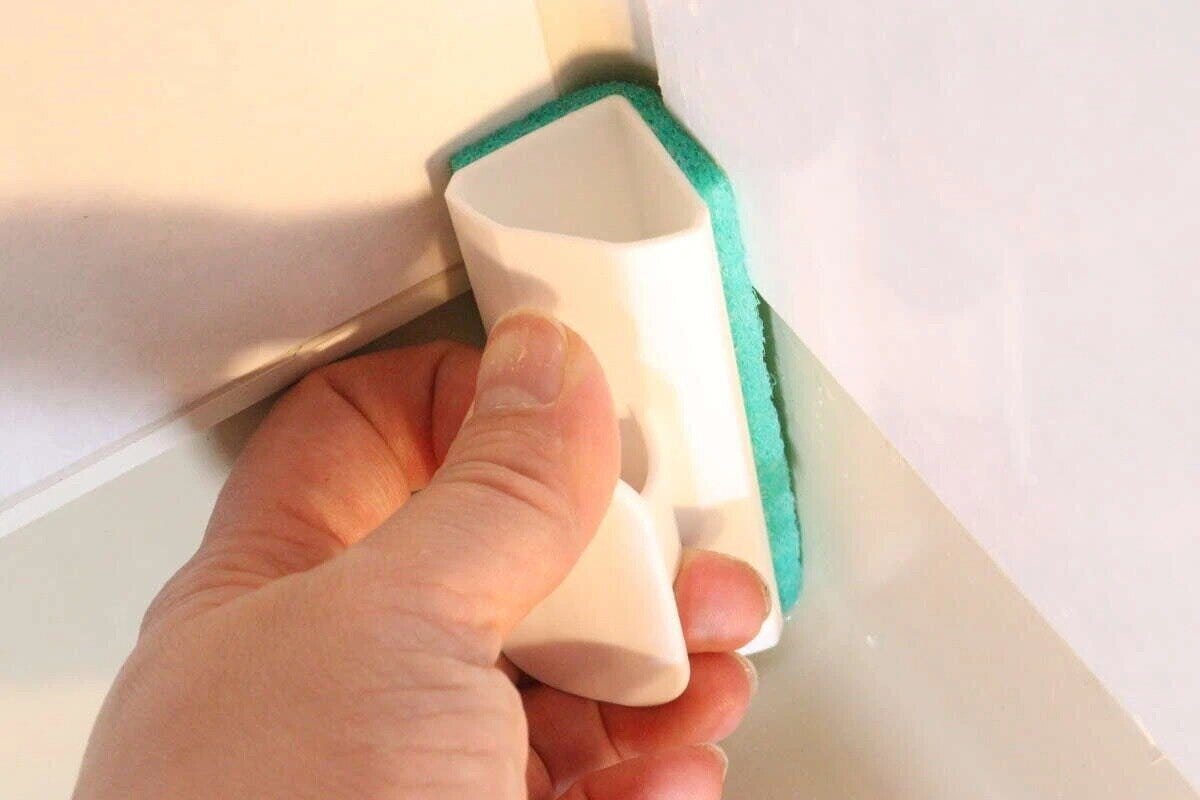 手で浴室ブラシを使い浴室の壁の角を掃除している様子 手で浴室ブラシを使い浴室の壁の角を掃除している様子