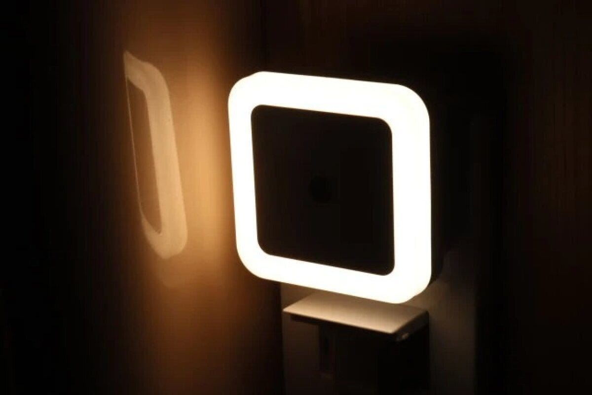 コンセントに差し込まれた白いナイトライトが、暗い部屋の壁を電球色の光で照らしている