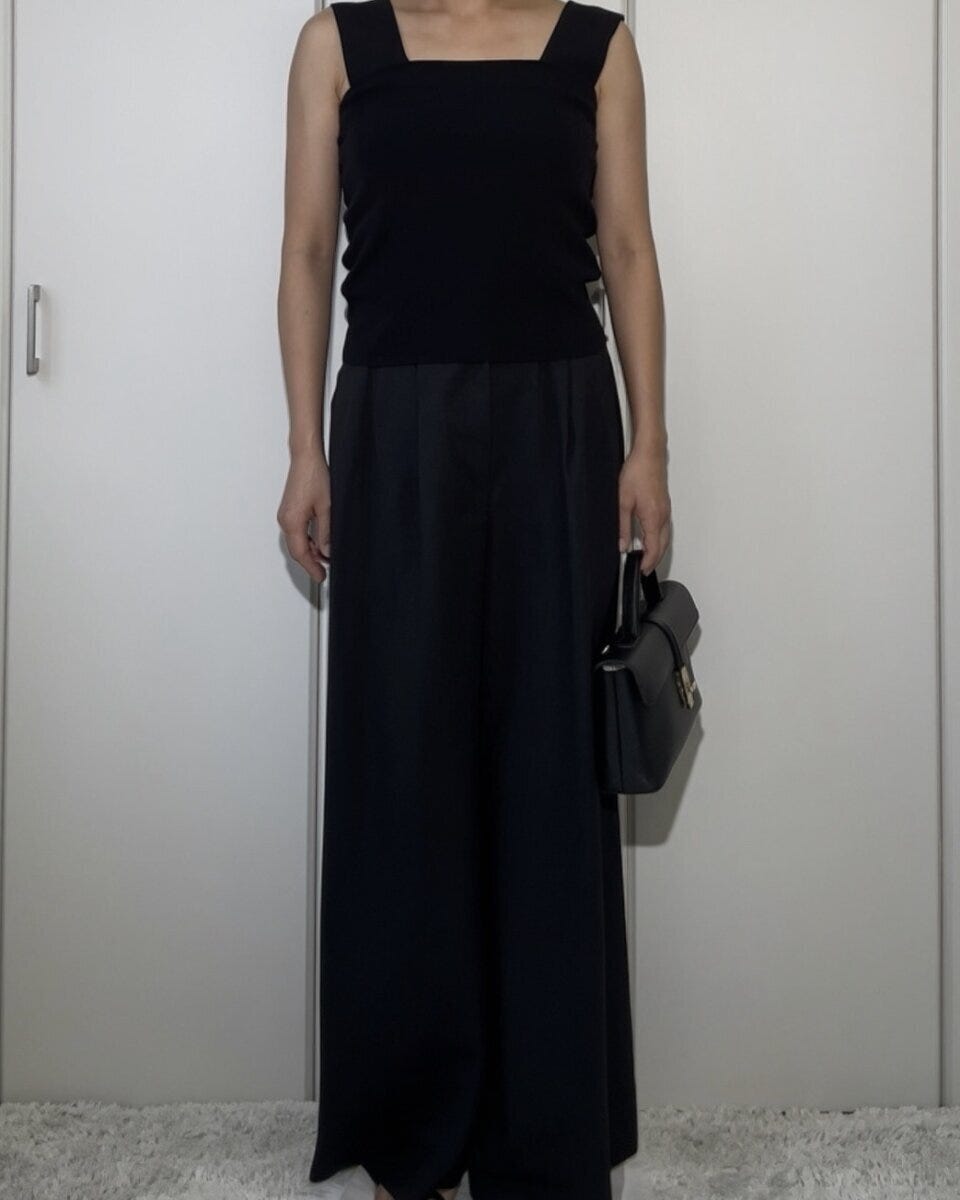 黒いニットインナーをアウトで着用し黒いワイドパンツと合わせたNGコーデの女性 黒いニットインナーをアウトで着用し黒いワイドパンツと合わせたNGコーデの女性
