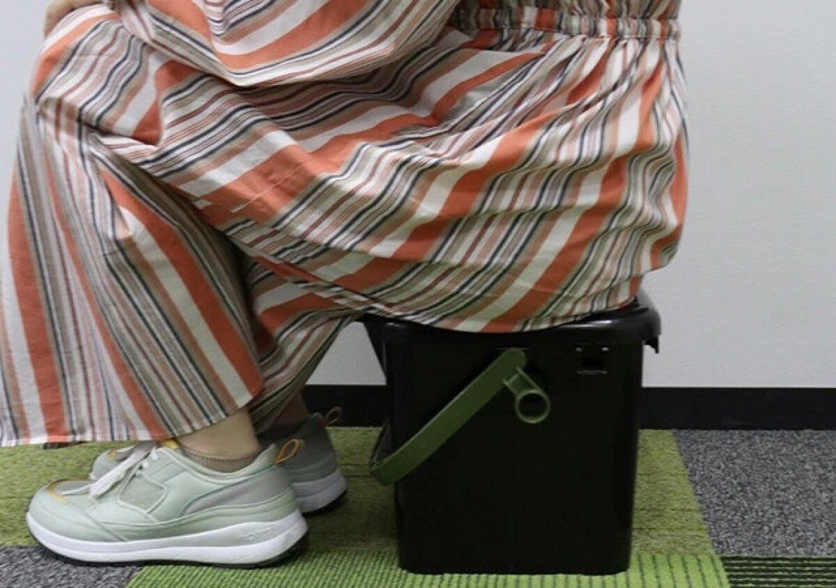 ストライプのパンツを履いた女性が黒い座れるボックスに座っている