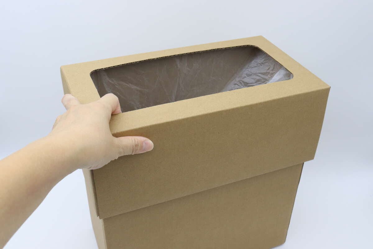 女性の手がゴミ袋をセットしたダストボックスにフタをかぶせている