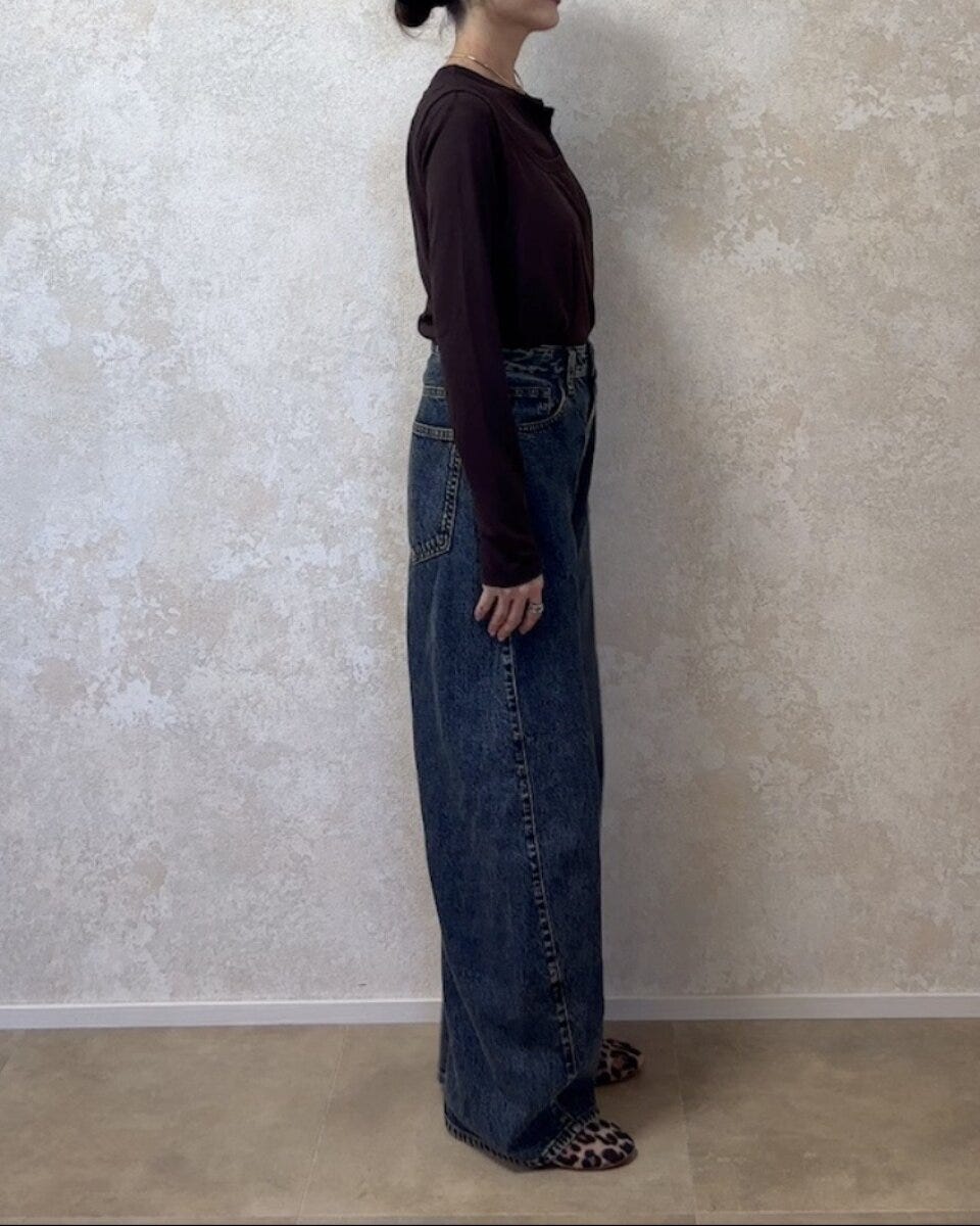 ブラウンのトップスとデニムを合わせた女性の横向きの全身写真