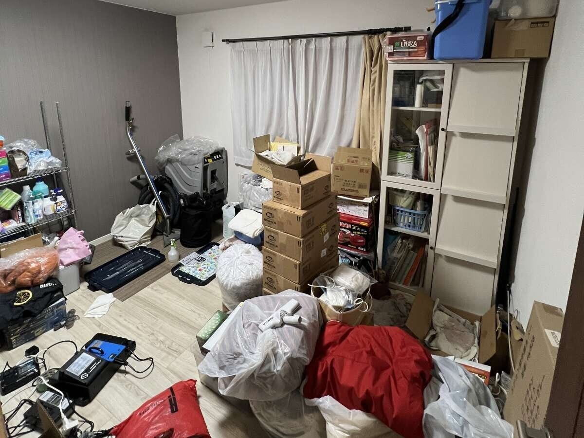 段ボールやゴミ袋、物が床に散乱し雑然とした部屋の様子