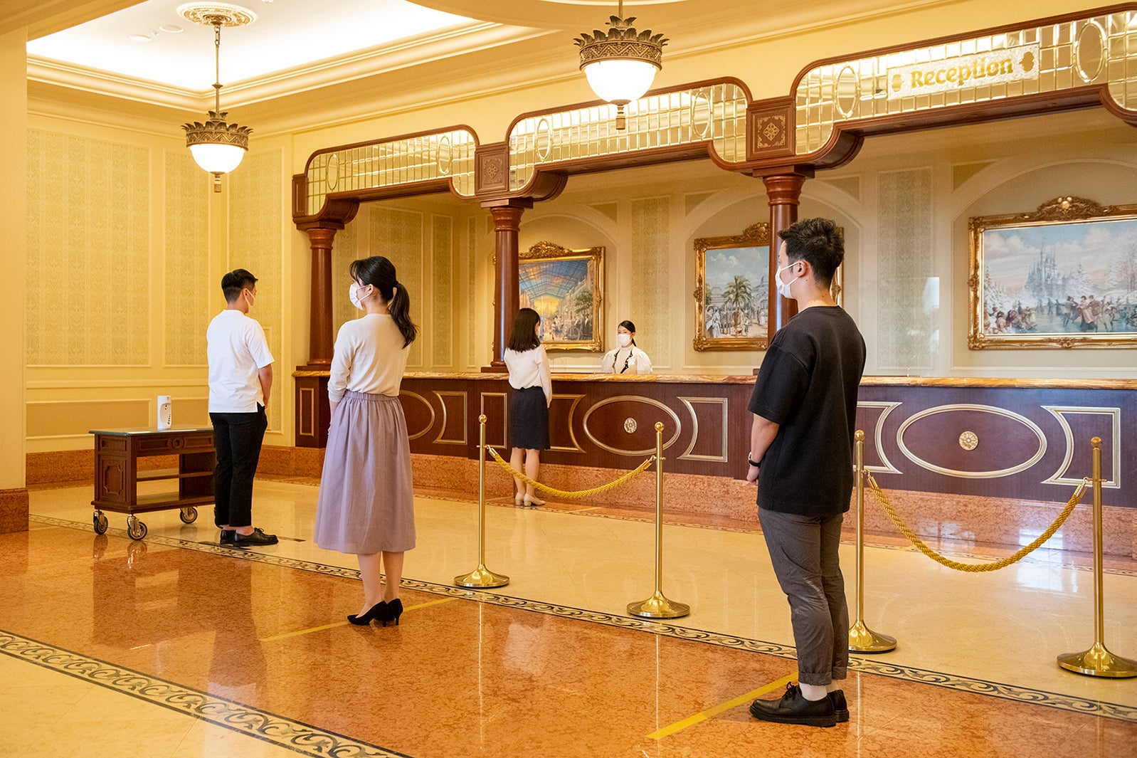 フロント前のソーシャルディスタンスを確保したチェックインの列のイメージ（C）Disney