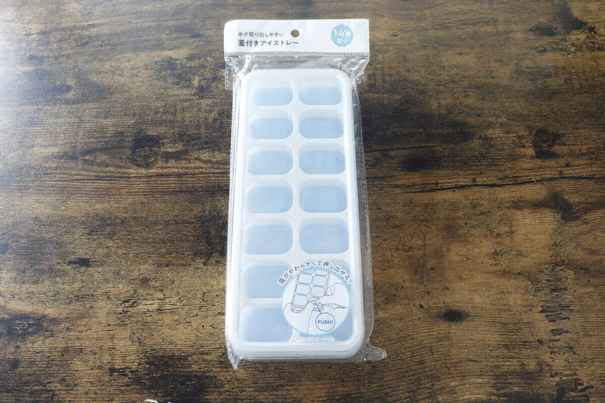 パッケージに入ったセリアの氷が取り出しやすい蓋付きアイストレーが木目のテーブルに置かれている パッケージに入ったセリアの氷が取り出しやすい蓋付きアイストレーが木目のテーブルに置かれている