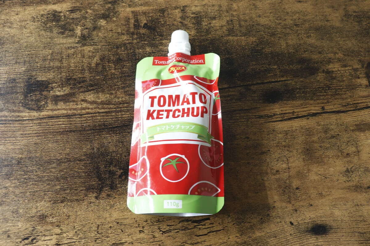 赤と緑のパウチ入りトマトケチャップが木目のテーブルに置かれている俯瞰写真