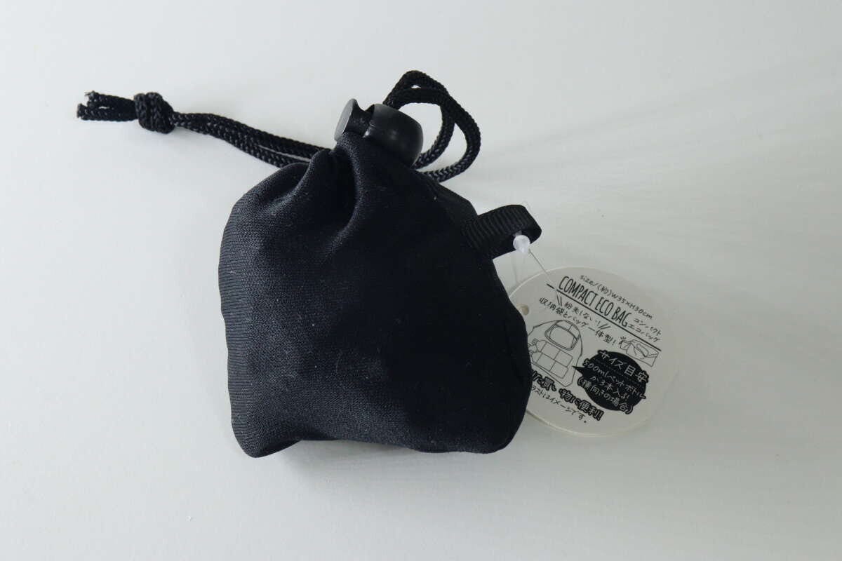 黒い巾着型に畳まれたコンパクトエコバッグと商品タグ