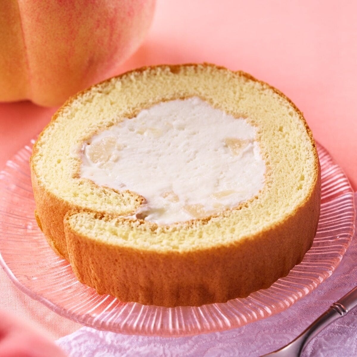 透明な皿に盛られた白桃のロールケーキ