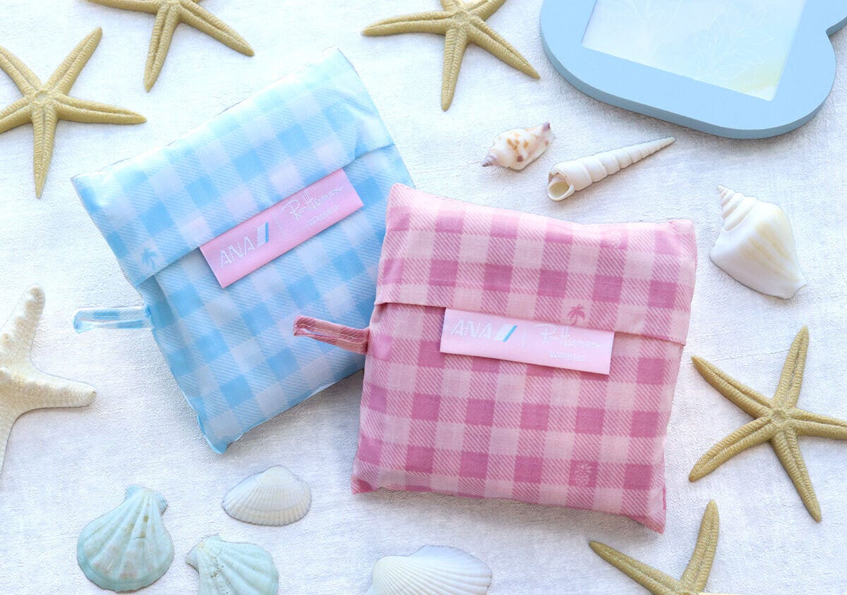 ピンクとライトブルーの折りたたんだエコバッグポーチをヒトデや貝殻と並べて撮影した俯瞰写真