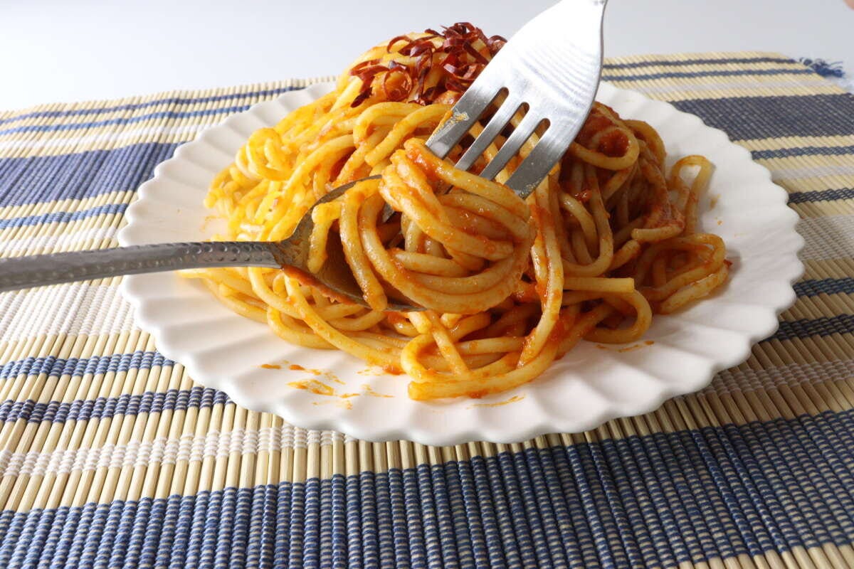 槌目風デザートスプーンとフォークでトマトソースのパスタを食べている