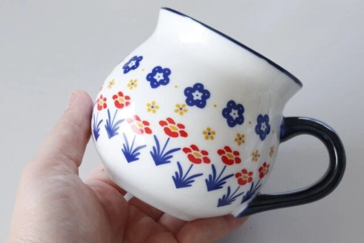 女性の手で持たれたポーリッシュ風の花柄マグカップ 女性の手で持たれたポーリッシュ風の花柄マグカップ
