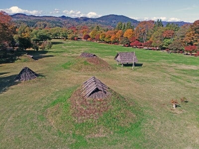 御所野遺跡、中央と上が土屋根の竪穴建物、左が伏屋式の竪穴建物、右が高床建物。出典：JOMON ARCHIVES（縄文遺跡群世界遺産保存活用協議会撮影）