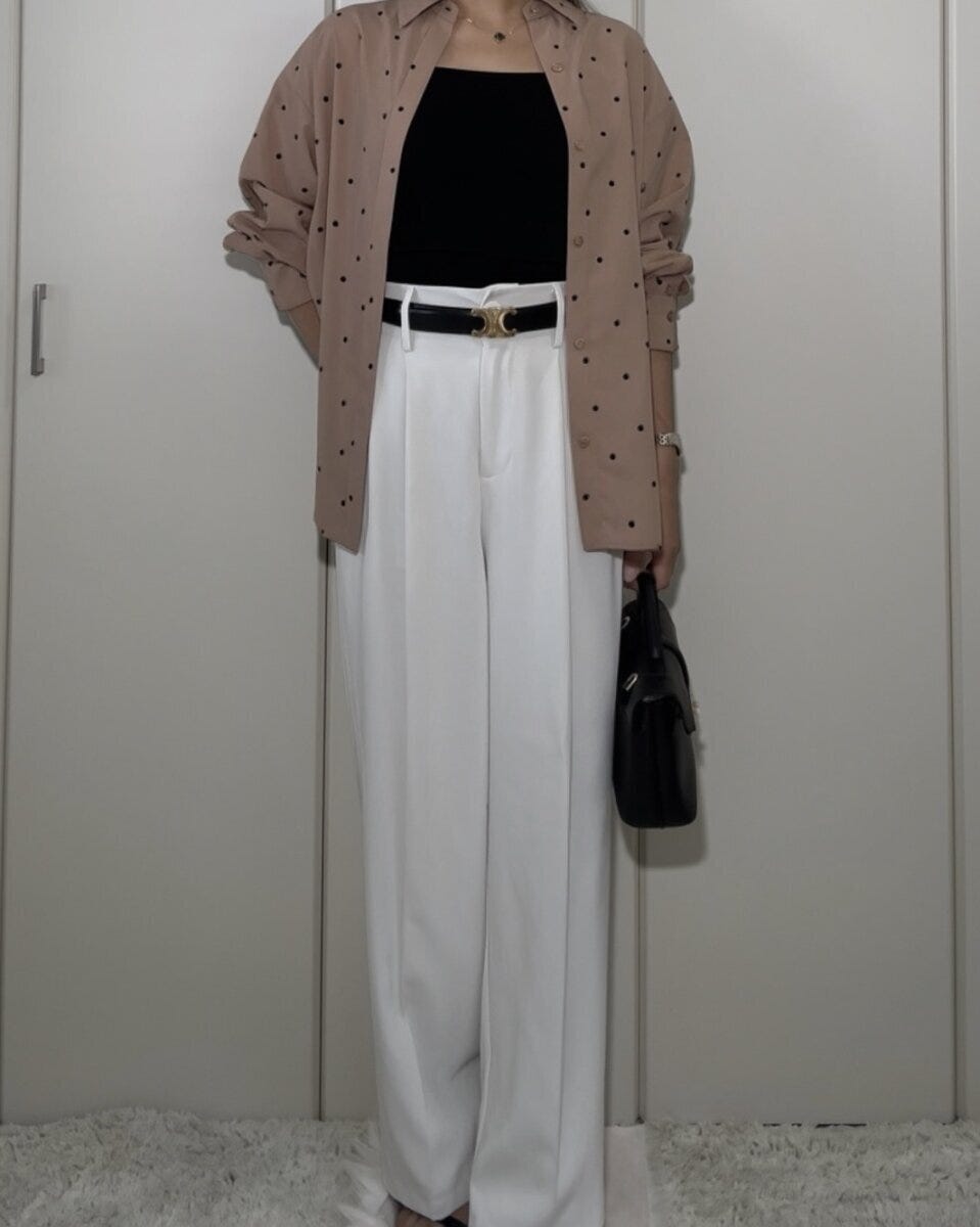 黒いニットインナーと白いワイドパンツにベージュのドット柄シャツを羽織る女性 黒いニットインナーと白いワイドパンツにベージュのドット柄シャツを羽織る女性