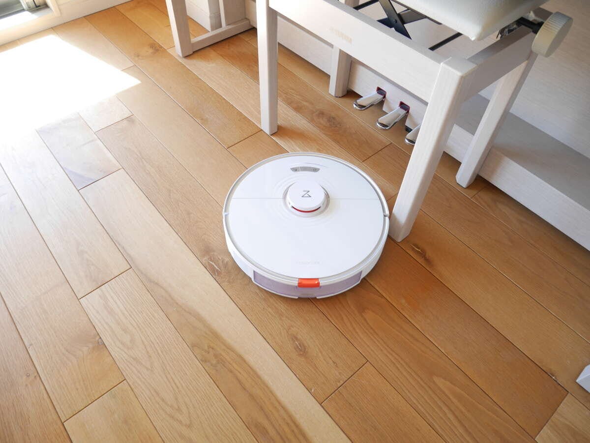 無垢材フローリングの上で稼働している白いロボット掃除機