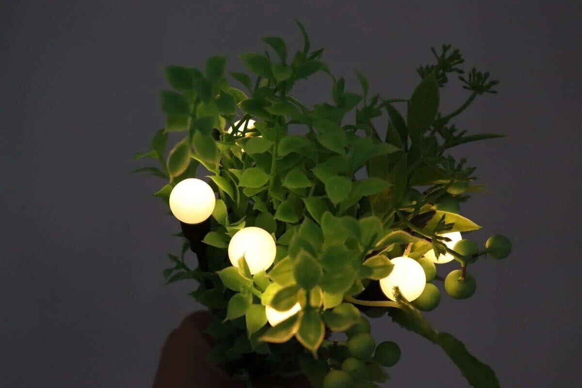 植物の中に挿されたデザインソーラーライト（蛍）が丸く光る様子