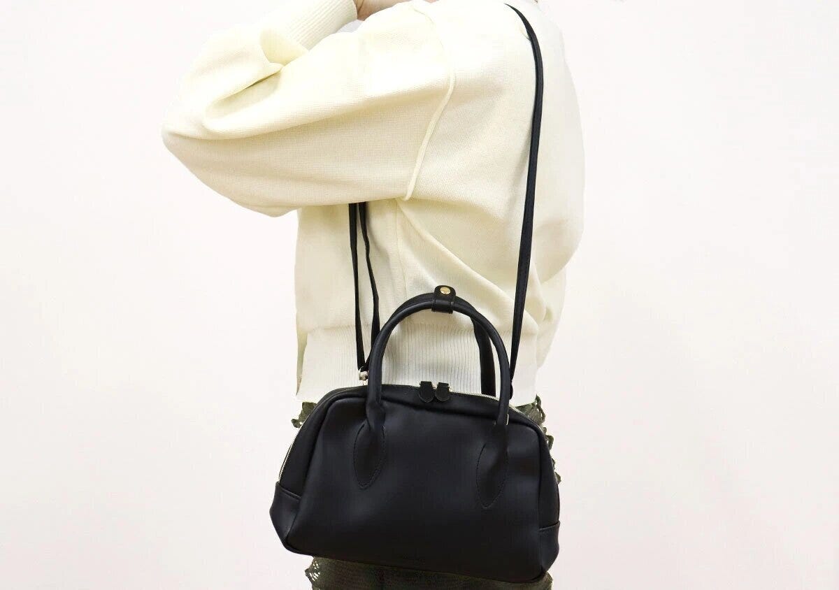 ánuansの黒ボストンショルダーバッグを斜めがけしている女性の後ろ姿