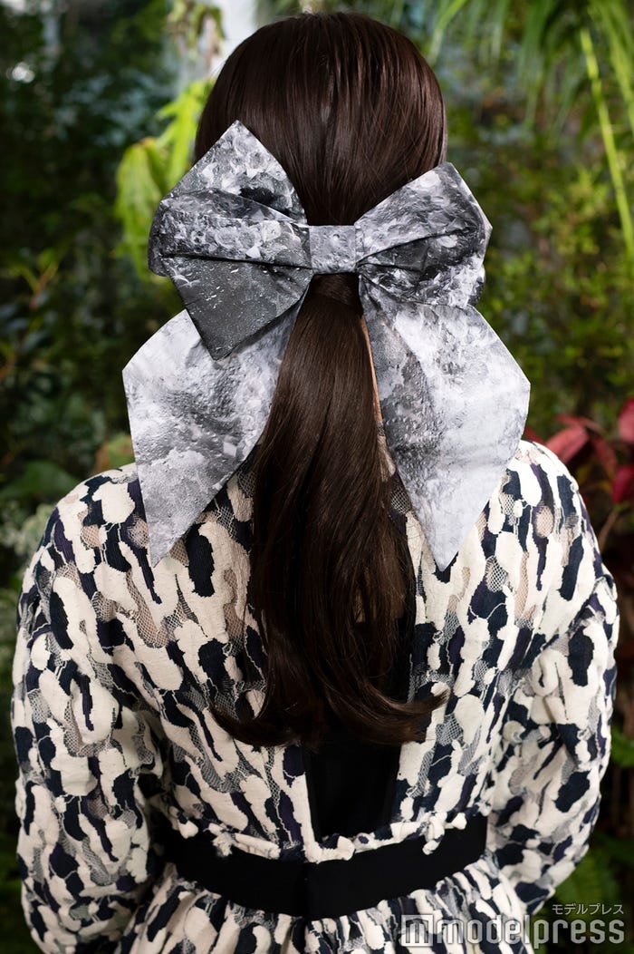 【長濱ねる・ヘア】ジャガード織り総柄ワンピースと、落ち着きのある柄の大きなリボンに合うよう、ヘアはロングウィッグをつけました。下の方で結び、リボンの位置を下にすることで、大人可愛いイメージにしました。(C)モデルプレス