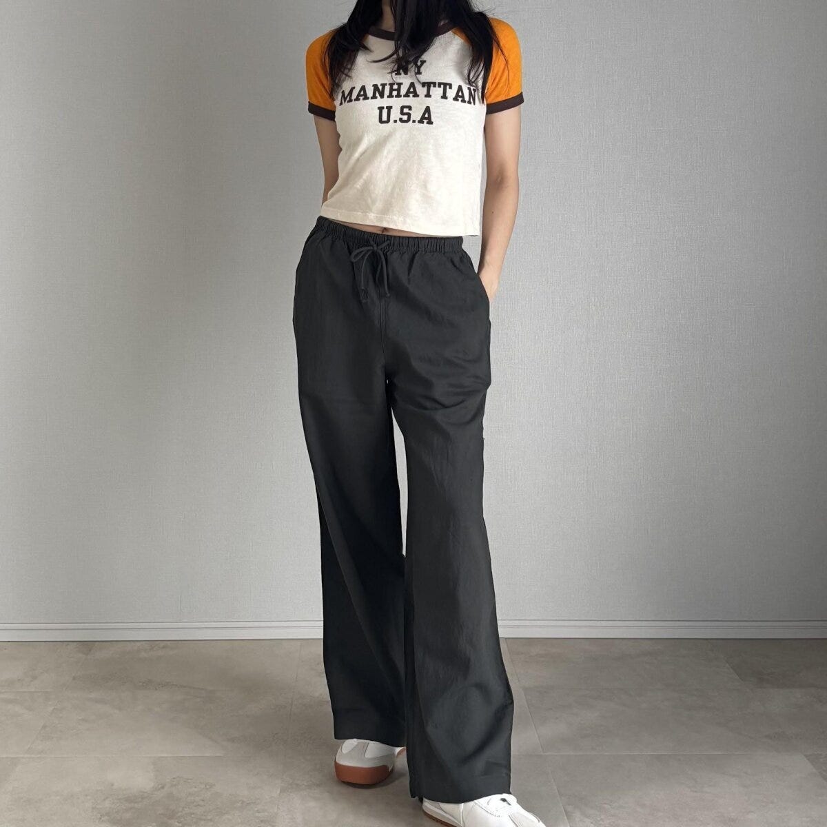 ロゴ入りミニTシャツとダークグリーンのリネンパンツを着用した女性 ロゴ入りミニTシャツとダークグリーンのリネンパンツを着用した女性
