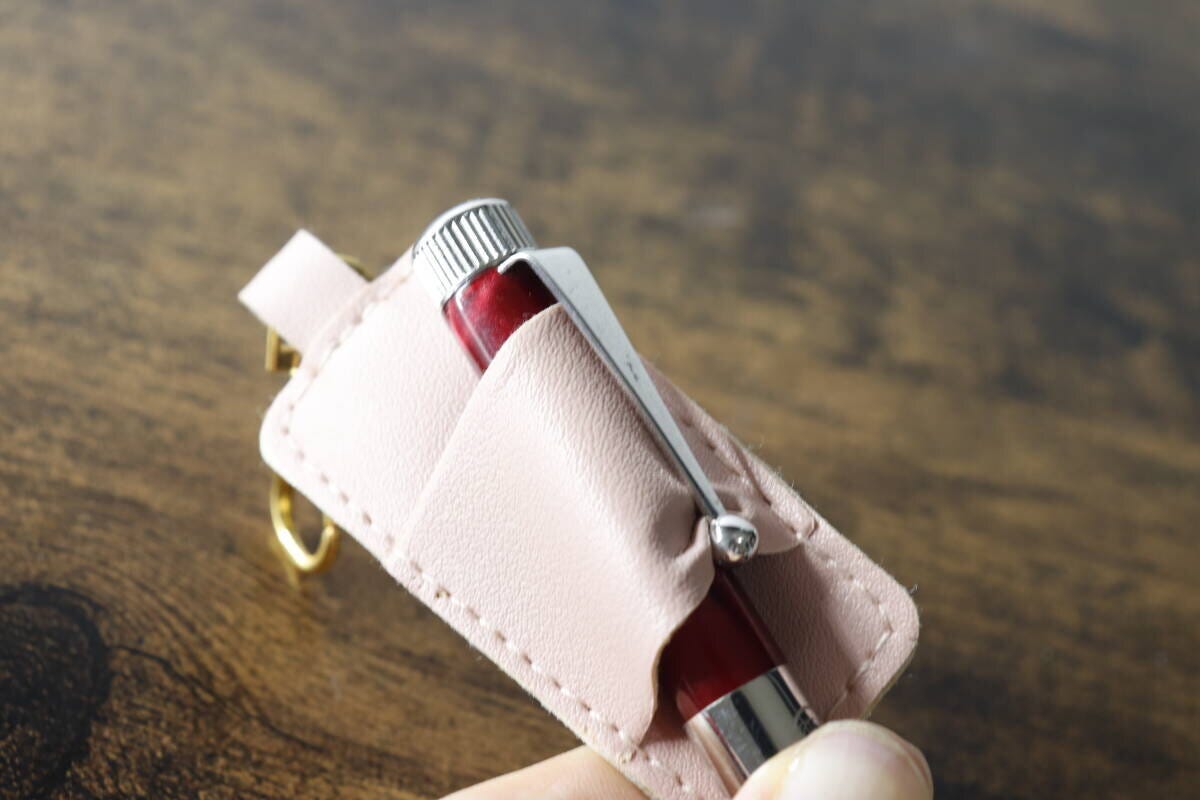 赤いペンをピンクのペンホルダーに差し込んでいる 赤いペンをピンクのペンホルダーに差し込んでいる