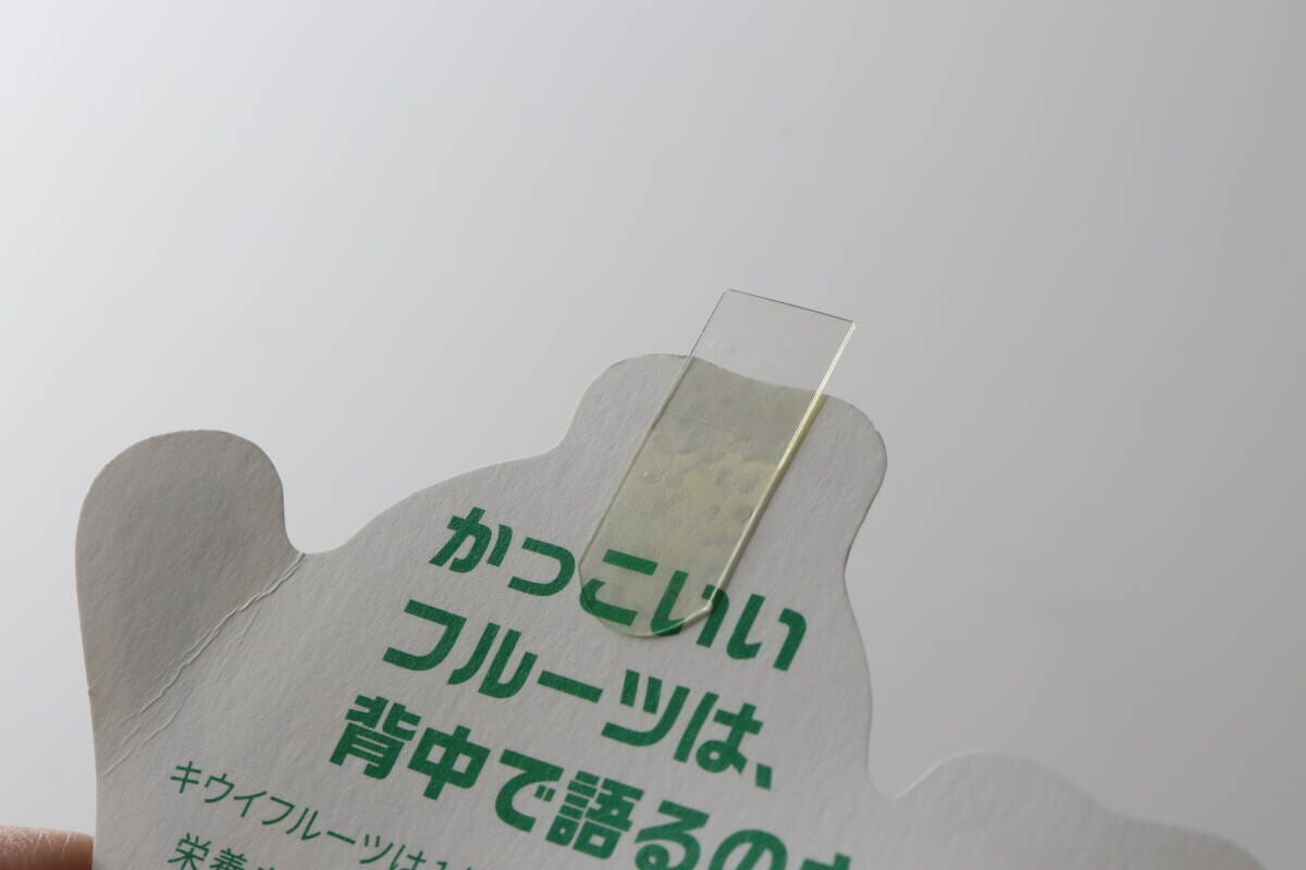 「かっこいいフルーツは、背中で語るのさ」と書かれたカードの裏面に透明な伸びるテープを貼っている