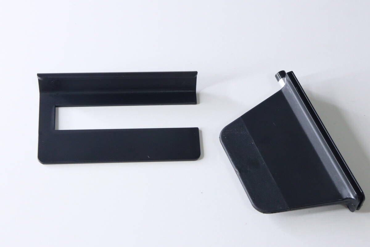 白い背景に置かれた、分解された状態の黒いスマホスタンドのパーツ2つ。