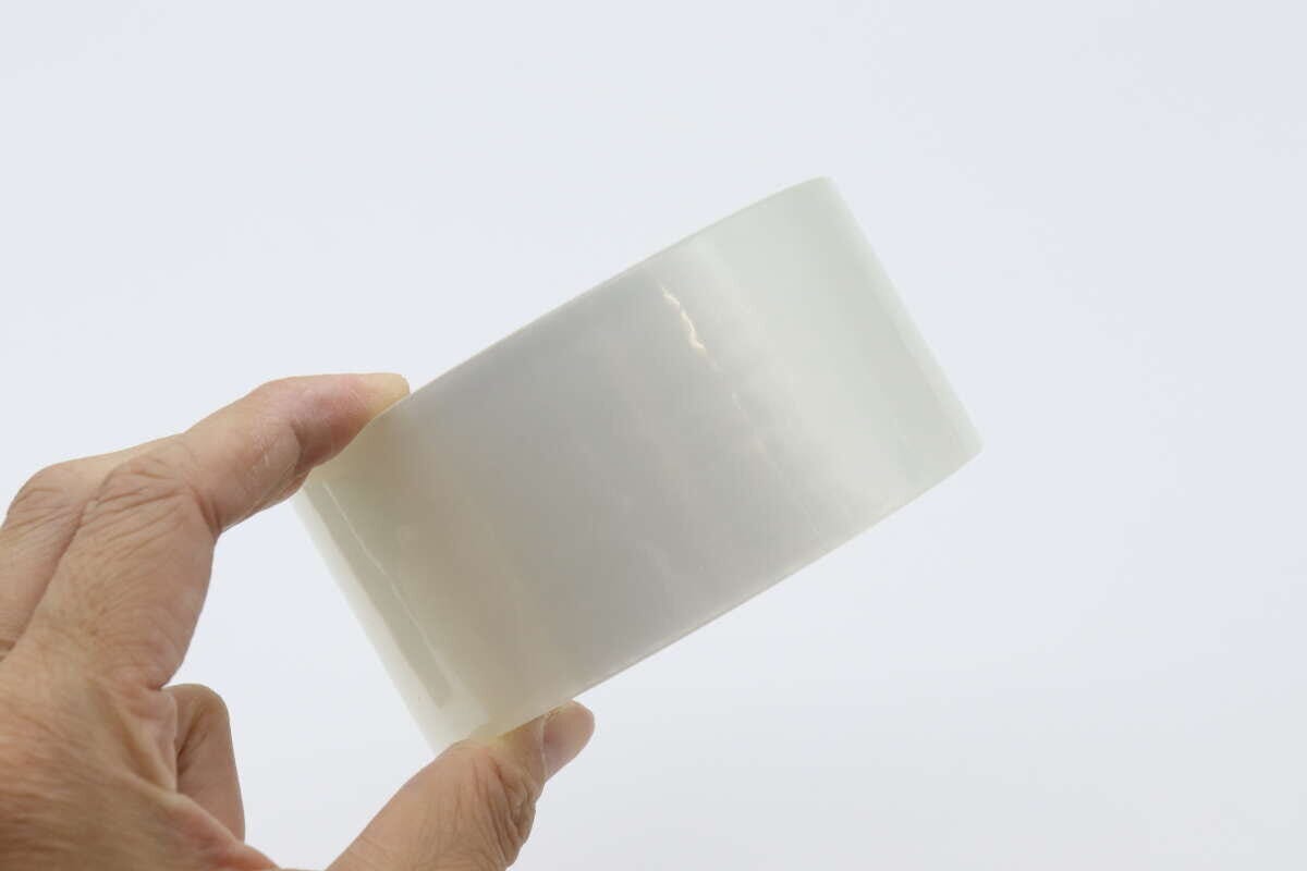透明な梱包テープのロールを右手が横から持っている様子 透明な梱包テープのロールを右手が横から持っている様子