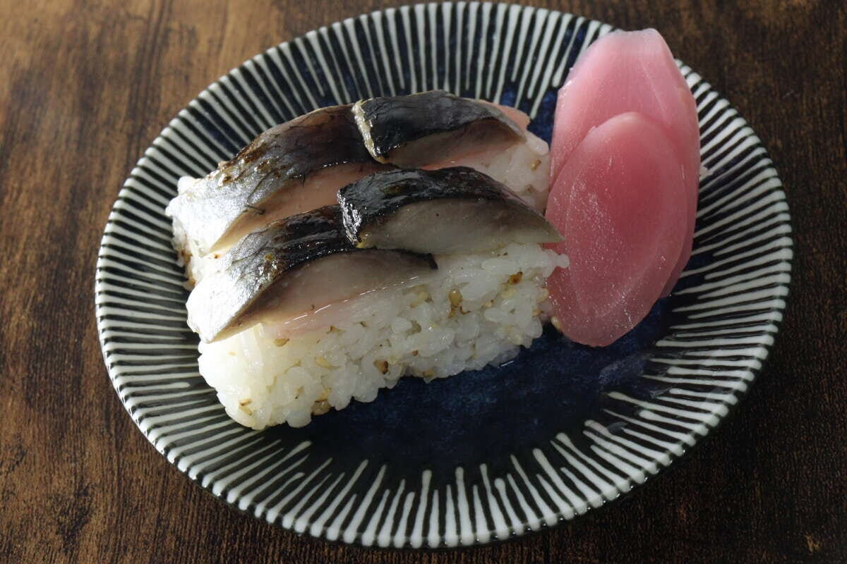 縞模様の皿に盛り付けられた鯖の押し寿司と、付け合わせのピンク色の新生姜スライス 縞模様の皿に盛り付けられた鯖の押し寿司と、付け合わせのピンク色の新生姜スライス