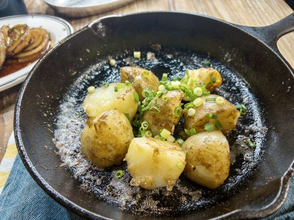 完成した皮付き新じゃがのフライパン蒸し焼きバター醤油に青ねぎを散らした俯瞰写真