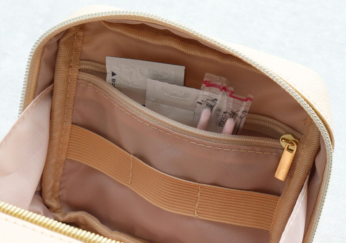 ベージュのハートカットポーチを開けた内部。ファスナー付きポケットに錠剤のシートが収納されている。