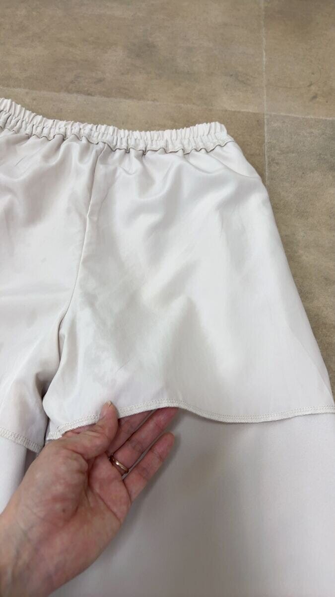 ワイドパンツの裏地を指でめくって見せている