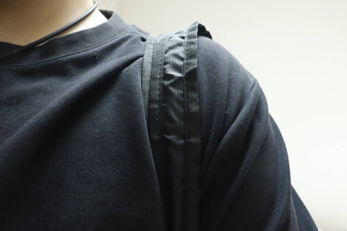 黒いTシャツの人がバッグを肩にかけショルダーベルトが写る