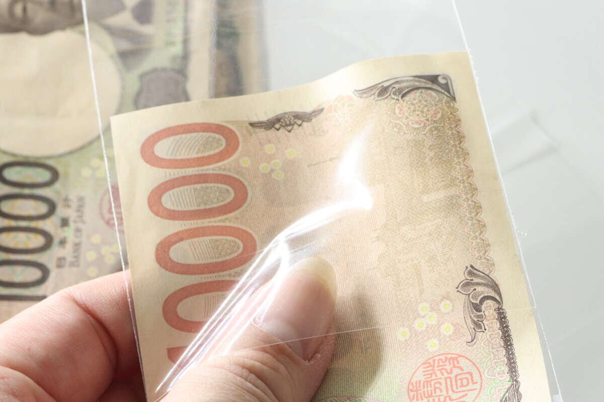 1万円札を透明な袋に入れている手元