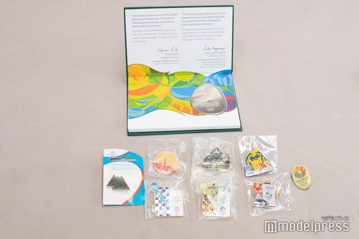 森アナが持参してくれた各大会でプレス向けに配られるバッチ。毎回デザインが違うそうです!(C)モデルプレス